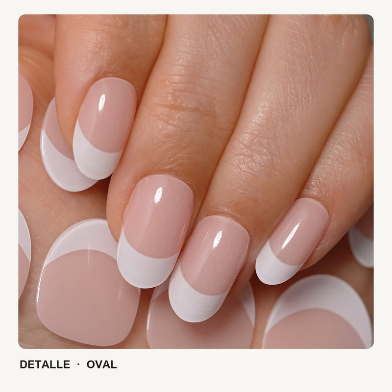 Detalle de uñas de forma oval, en base rosa y punta blanca de manicura francesa, con acabado brillante.