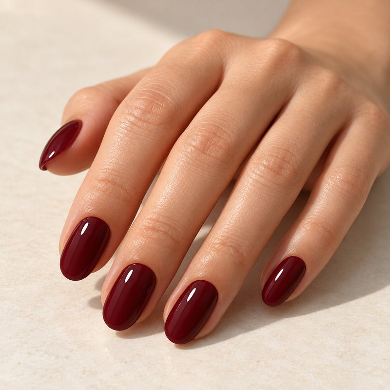 Mano con extensiones de forma oval, en granate oscuro, con acabado brillante.